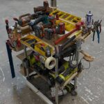 A wooden mobile tool cart filled with various power tools and organizers in a workshop.